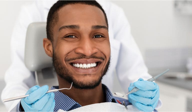 A smiling man relaxes in a dentist chair, reflecting a comfortable and pleasant visit to the dentist.